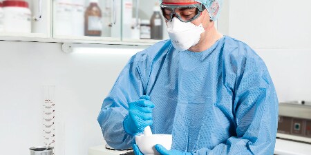 healthcare worker wearing PAPR with hood helping patient

